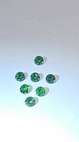 Six round green gemstones on white background