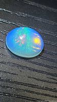 Top view of oval cabochon opal showing multicoloured flash