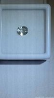 Loose oval faceted near-colorless sapphire in gem display box