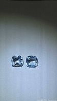 Pair of cushion-cut sky blue topaz stones on neutral background