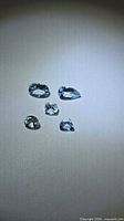 Five faceted aquamarines arranged on neutral background