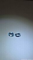 Two oval aquamarine gemstones on neutral background