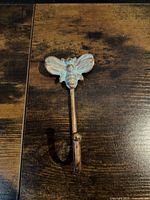 Front view of cast metal bee motif wall hook showing finish and shape