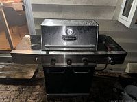Front view of Cuisinart gas grill showing four burner knobs, lid, thermometer and side burner cover