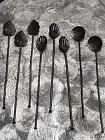 Eight silver stir sticks showing three different finial designs