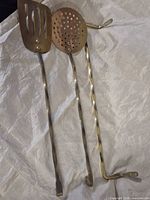 Full view of two long-handled utensils showing heads and hooks
