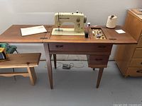 Full view of Bernina sewing machine mounted in wood cabinet with leaves extended, accessories visible