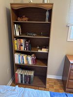 Front view of brown five-shelf bookcase showing shelves and arched top
