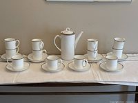 Full set showing coffee pot, eight cups and eight saucers laid out