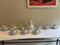 Full set laid out: teapot, 8 cups, 8 saucers