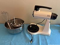 Stand mixer with bowls and attachments displayed