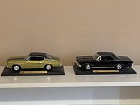 Both model cars on shelf showing size and stands