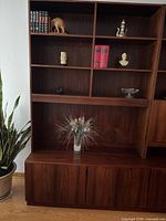 Front view of teak wall unit showing shelves and lower cabinet doors closed