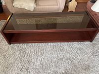 Top view of rectangular wood coffee table with smoked glass insert and lower shelf