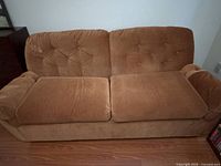 Front view of orange corduroy sofa with seat cushions and tufted back