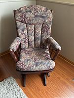 Front view of wooden rocking chair showing floral upholstery and rocker rails