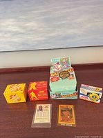 Four boxed card sets and visible sleeved cards on table