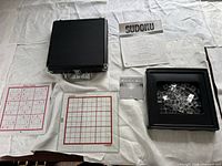 Full set showing hard case, glass board, tiles tray, puzzle sheets, booklet