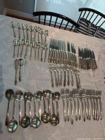 Full layout of flatware set showing spoons, knives, forks and serving pieces