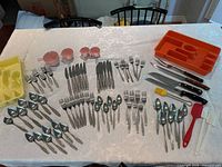 Full layout of flatware, kitchen utensils, trays on table
