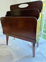 Front three-quarter view of walnut magazine rack showing compartments and legs