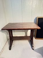 Front view of solid wood side table showing trestle legs and lower shelf