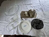 All six bakeware pieces laid out: CorningWare dish, two glass rectangles, glass oval, dark Bundt, gold beehive pan