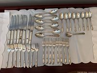 Full view of all knives, forks, tablespoons, teaspoons and sugar spoon laid out