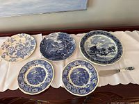 Five Delft-style plates and knife arranged on cloth