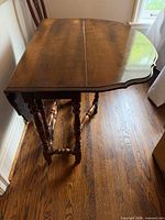 Table viewed from side with one leaf raised showing turned legs and stretcher