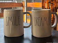 Front view of both mugs showing text designs
