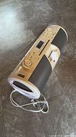 Cylindrical boombox showing control panel, speakers, antenna, power cord