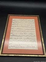 Full view of framed sheet music with orange mat and gold frame