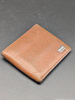 Front view of brown leather bifold wallet with logo plaque