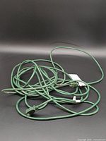 Coiled green indoor extension cord with plug and receptacle visible