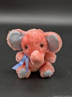 Front view of pink elephant plush showing ribbon, ears, eyes
