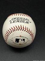 Top view showing Official League OLB3 stamping, red stitching, MLB logo, 5-oz weight, cork & rubber center note
