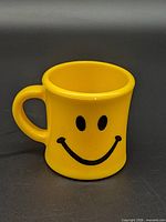 Front view of yellow smiley face mug