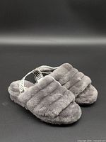 Pair of grey UGG fuzzy slide slippers showing top and side views