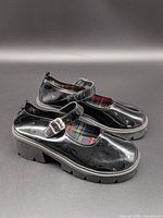 Side view of both shoes showing glossy finish, buckle strap and platform sole