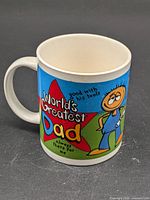 Front of ceramic mug showing "World's Greatest Dad" text and cartoon dad