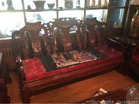 Full front view of carved wooden couch showing frame, backrest and seat cushions