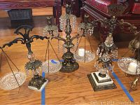 Full view of both the scales and candle holder on wooden floor showing detailed metalwork, glass plates, and bases