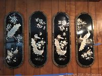 Four rectangular wood wall art panels with rounded tops, black lacquer background, mother-of-pearl inlay peacock and floral designs, arranged side by side on wood floor.