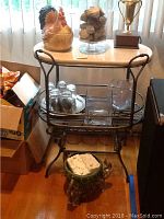 Full view of marble top table with all items on and under it including rooster cookie jar, glass jar with stones, bowling trophy, drink glasses, tray with glasses, and decorative stone.
