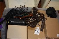 Tote containing extension cords, projector lights, and wires with boxes nearby