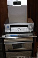 Stacked stereo components including Pioneer SX7 receiver, equalizer, and cassette player on glass shelving unit.