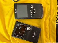 Front view of Kodak pocket camera and Cowon iAudio device on yellow cloth