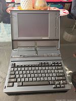 Laptop open showing keyboard, screen, and built-in printer mechanism