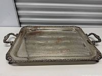 Top view of rectangular silver-plated tray showing engraved surface, handles and border